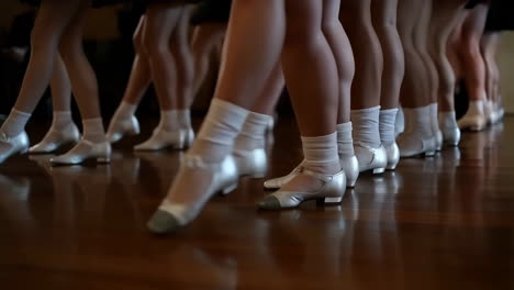 a line of dancers' legs and feet in formation on a wooden floor