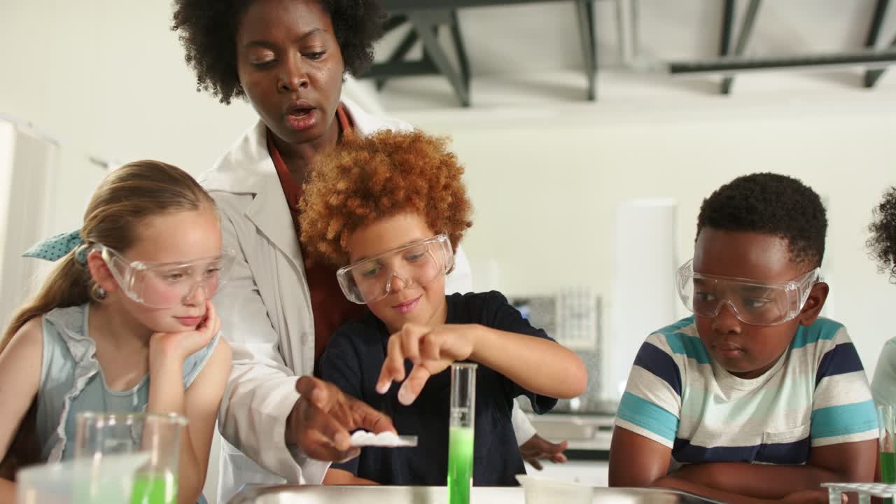 Teacher guiding 3 children placing tablet into cylinder in lab wearing goggles observing reaction