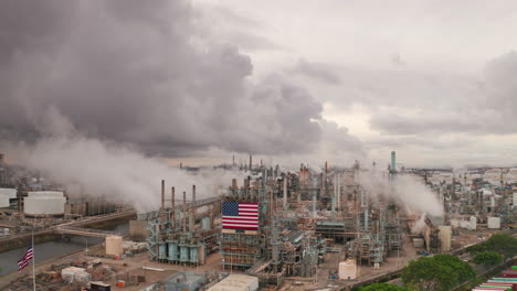 transmisión de vapor de chimeneas en la fábrica americana con bandera estadounidense y nubes grises