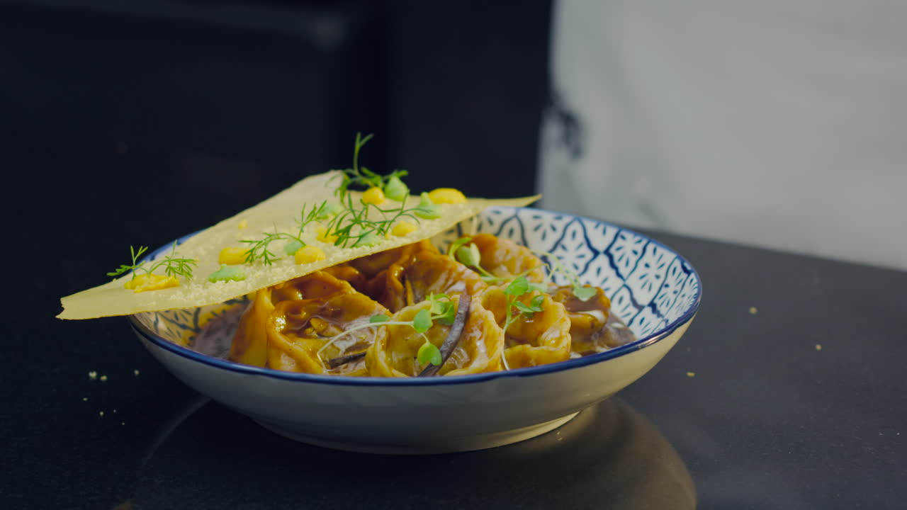 Gourmet ravioli covered with creamy sauce and decorated with fresh herbs, presented on an elegant plate for professional culinary content