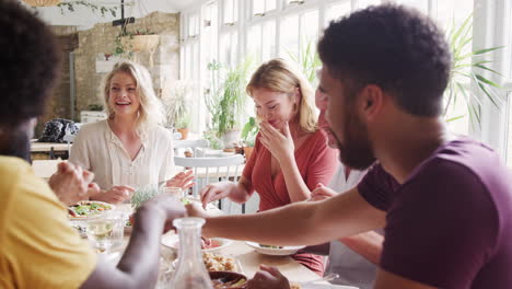 A-multi-ethnic,-mixed-age-group-of-adult-friends-eating-tapas-together-at-a-table-in-a-restaurant,-close-up,-selective-focus