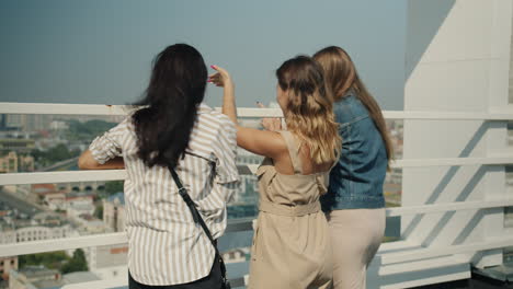 three women enjoying a city view from a rooftop