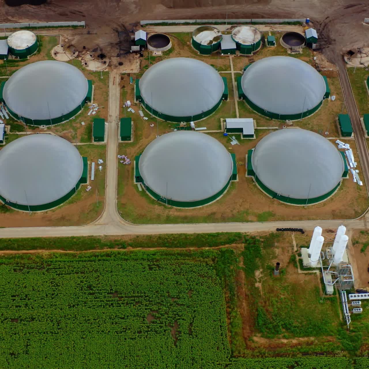 Modern construction of biogas plant. Storage tanks on green field. Bio energy production plant. Top aerial view.