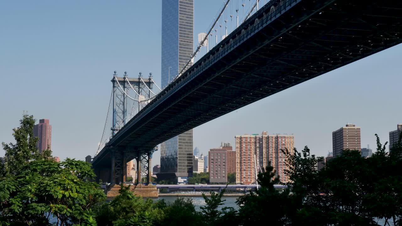 Slow motion landscape of Manhattan Bridge crossing landmark downtown Brooklyn East River New York City buildings skyline USA America infrastructure tourism transport