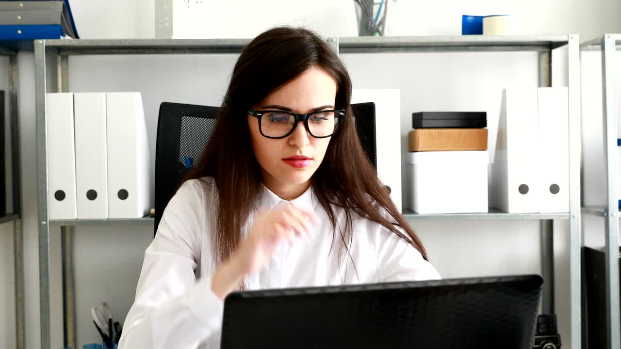 mujer de negocios quitándose las gafas negras y trabajando en una computadora portátil en una oficina moderna