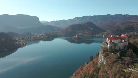 Aerial-view-of-Lake-Bled-castle-with-the-drone-flying-towards-and-past-the-castle-with-the-lake-and-iconic-church-of-Lake-Bled-island-in-Slovenia-in-the-background