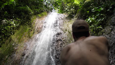 photographer taking photos up tropical jungle waterfall from behind slow motion