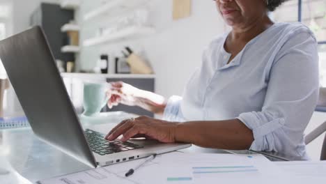 mujer de raza mixta mayor usando una computadora portátil. distanciamiento social y aislamiento en cuarentena
