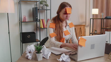 Exhausted-woman-freelancer-with-pasted-stickers-using-laptop-having-concentration-problem-in-office