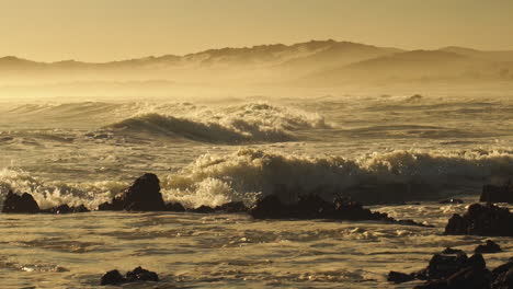 rough sea waves crashing on rocky shoreline during golden afternoon - wide static shot