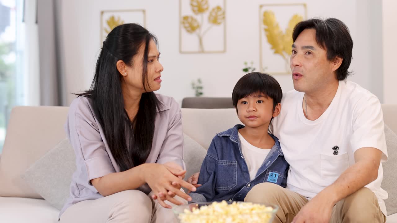 A family enjoys quality time on the couch, sharing popcorn and engaging in a lively discussion