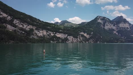 drone, aerial flight to a stand up paddler on a yellow stand up paddle, sup, in the middle of a lake in switzerland