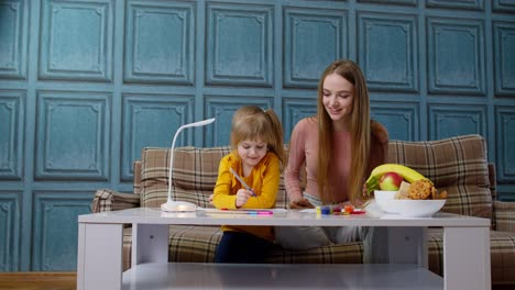 Encantadora-Madre-Niñera-Maestra-Ayudando-A-Su-Hija-Con-La-Tarea,-Aprendiendo-A-Escribir-En-Casa