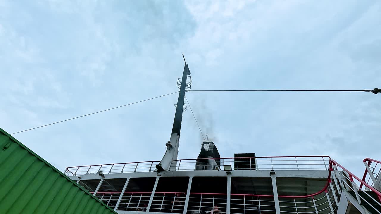 Smoke rises from a ferry chimney under a cloudy sky in Koh Samui, creating a dynamic scene with contrasting colors