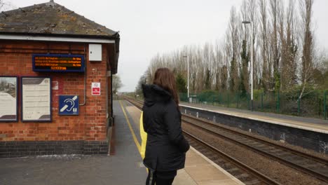 mother and daughter waiting for a train at an old village railway station