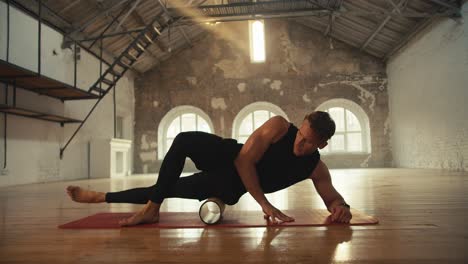 close-up shot of a young man in a black sports summer uniform kneading the muscles of his thighs with a special fitness cone