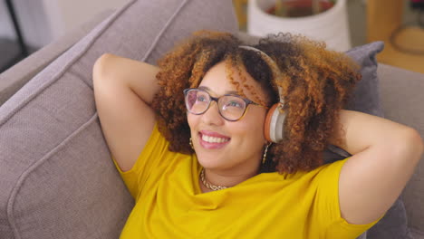 música, auriculares y mujer feliz relajarse en un sofá