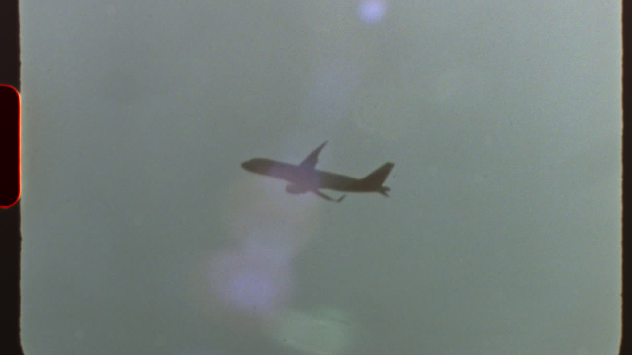 Filmed on super 8 film Vintage style commercial passenger jet soaring across cloudy sky, captured with nostalgic film grain and authentic light leaks reminiscent of analog cinematography