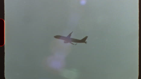 filmed on super 8 film vintage style commercial passenger jet soaring across cloudy sky, captured with nostalgic film grain and authentic light leaks reminiscent of analog cinematography
