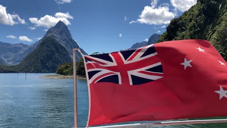neuseelands rote flagge auf einem kreuzfahrtschiff, das im wind am milford sound in fiordland, neuseeland, weht