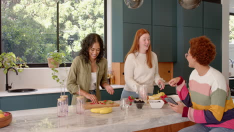 preparing fruit and smoothies, diverse female friends enjoying time together in kitchen