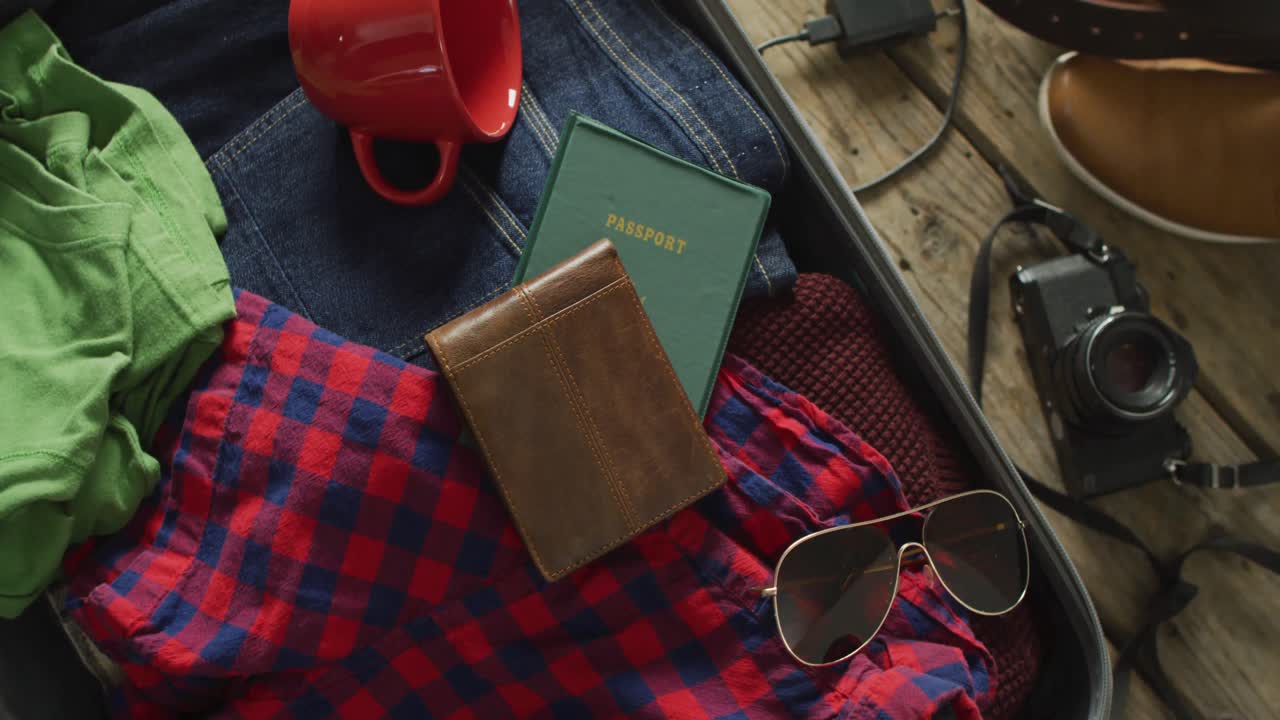 video de documentos, gafas, cámara, taza y ropa preparados para ser empacados en la maleta para el viaje
