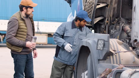 boss and worker checking the mechanics of a truck in a logistics park