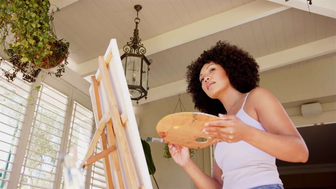 Painting on canvas, woman holding palette and focusing on her artwork