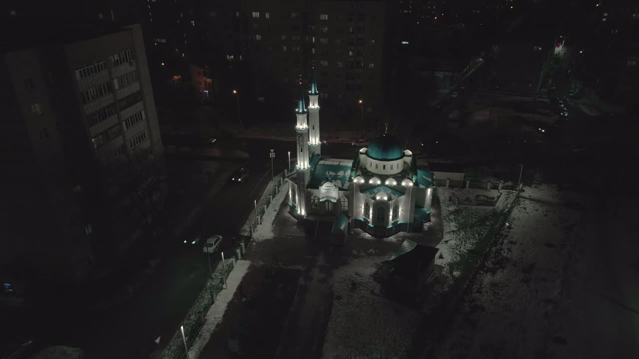 mezquita iluminada y pequeño parque en la ciudad de invierno de la noche