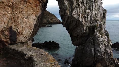 mirando a través de la formación de arcos rocosos hacia el mar irlandés en traeth, playa de porth wen