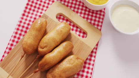 video of corn dogs with dips on a white surface