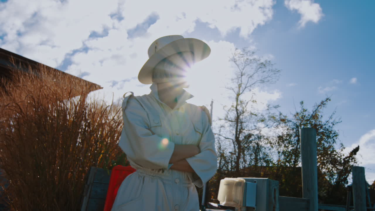 Portrait en contre-jour d'une femme en chapeau au bord de l'eau. Silhouette d'une femme portant une combinaison de safari et un chapeau, se détachant sur la lumière vive du soleil et le ciel bleu, sur une jetée de New York.