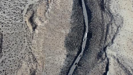 cars and public bus driving on desert highway road, aerial top down shot