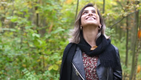 Brunette-girl-in-forest-lookings-happy-up-in-the-trees-and-leaf-is-falling-down