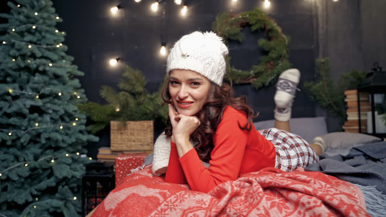 Young woman relaxing at Christmas. Elegant lady in red over christmas background