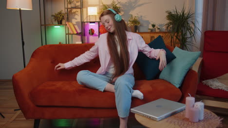 niño feliz y relajado con auriculares inalámbricos bailando escuchando su música rock n roll favorita en el sofá de casa