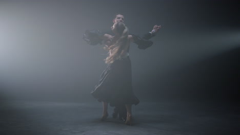 ballroom couple dancing valse on dark stage. sensual dancers waltzing indoors.