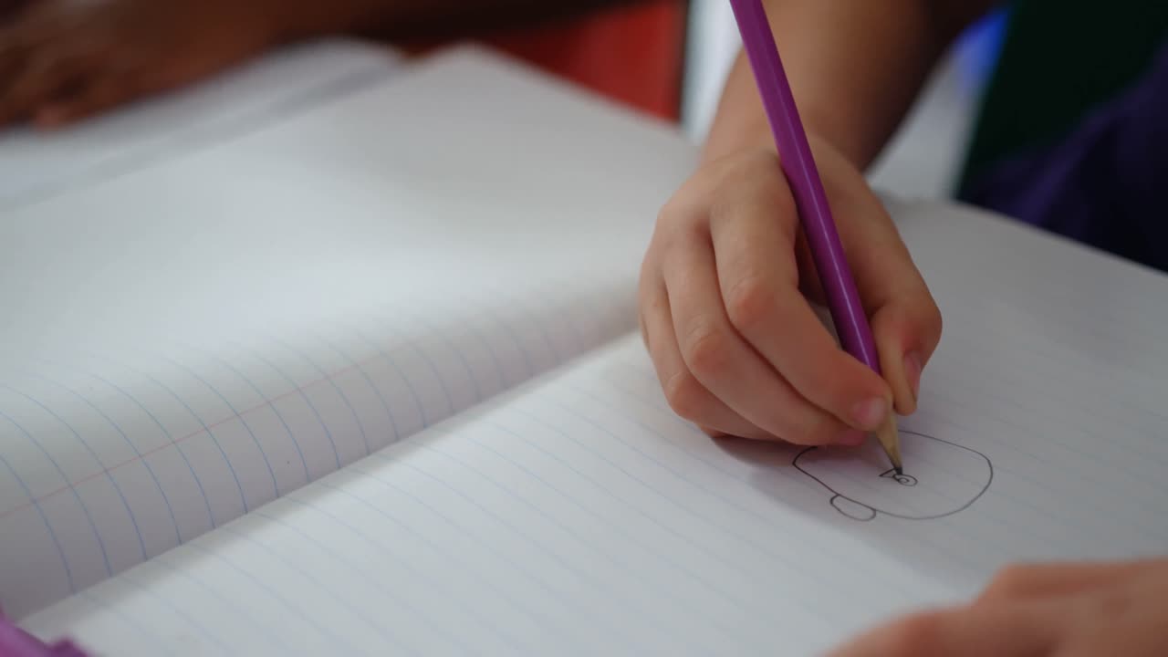 primer plano de un escolar dibujando en un cuaderno en el aula 4k