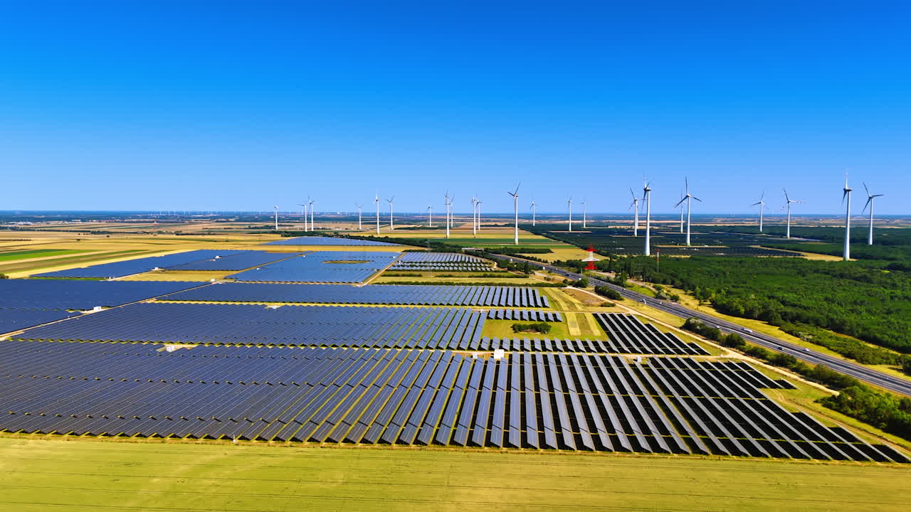 Yellow agricultural fields with solar panels. Wind farms located nearby. Aerial perspective