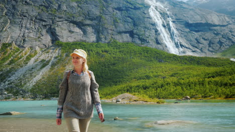 the traveler walks among the majestic cliffs with waterfalls and glaciers on top traveling in norway