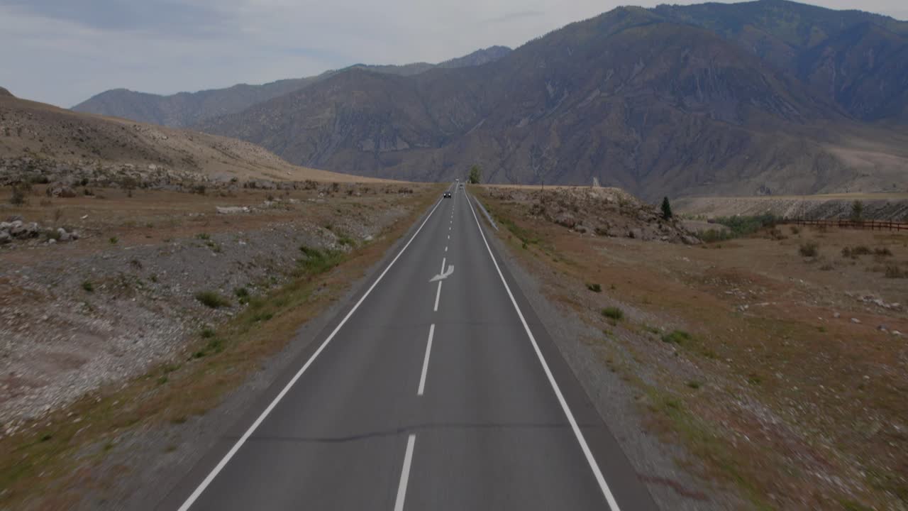 Riprese aeree con drone che mostrano dall'alto la strada Chuysky Trakt che attraversa i Monti Altai, Russia, con segnaletica stradale e terreno accidentato in una natura remota.