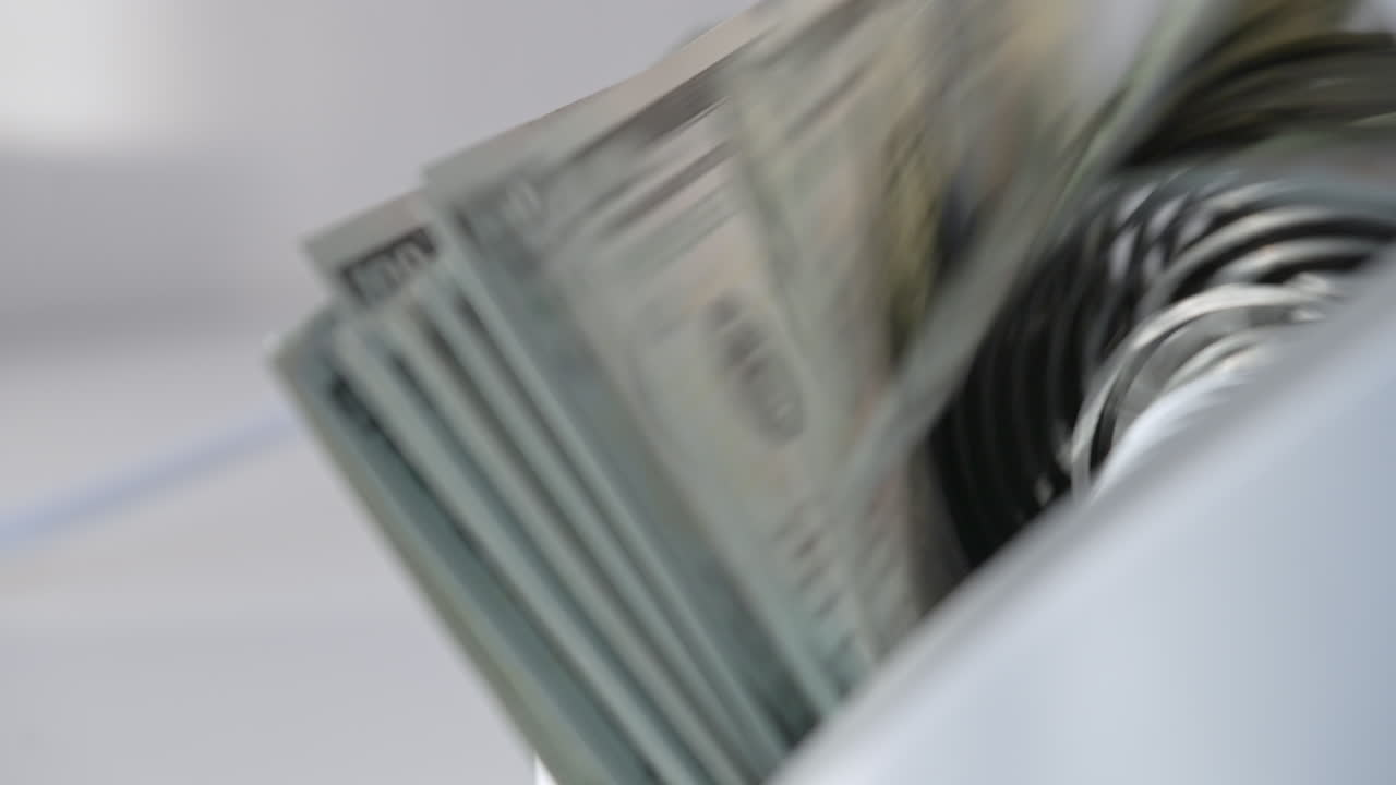 Hundred dollar bills falling on the holder in cash counting machine. Money counted machine stops working. Close up. Blurred backdrop.