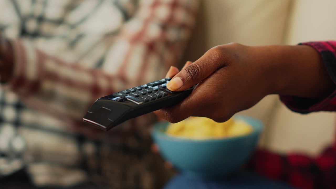 Young girlfriend using tv remote control to watch film