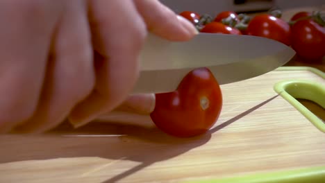 knife cuts tomato on wooden board slow motion with rotation tracking shot.