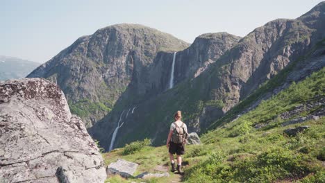 male hiker with backpack walking on a trail path leading to mardalsfossen waterfall in more og romsdal county, norway