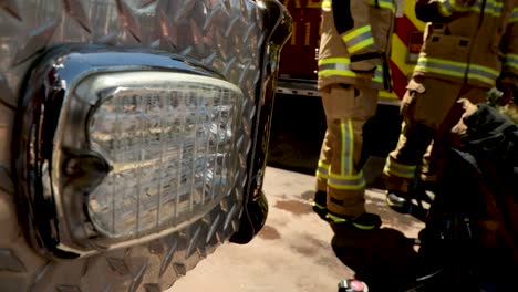 warning lights flash on a firetruck responding to an emergency with firefighters in the background