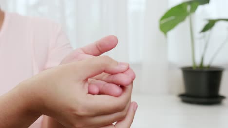 Asian-woman-doing-gentle-reflexology-on-her-palm-to-reserve-herself-in-physical-therapy-to-relieve-pain-from-work