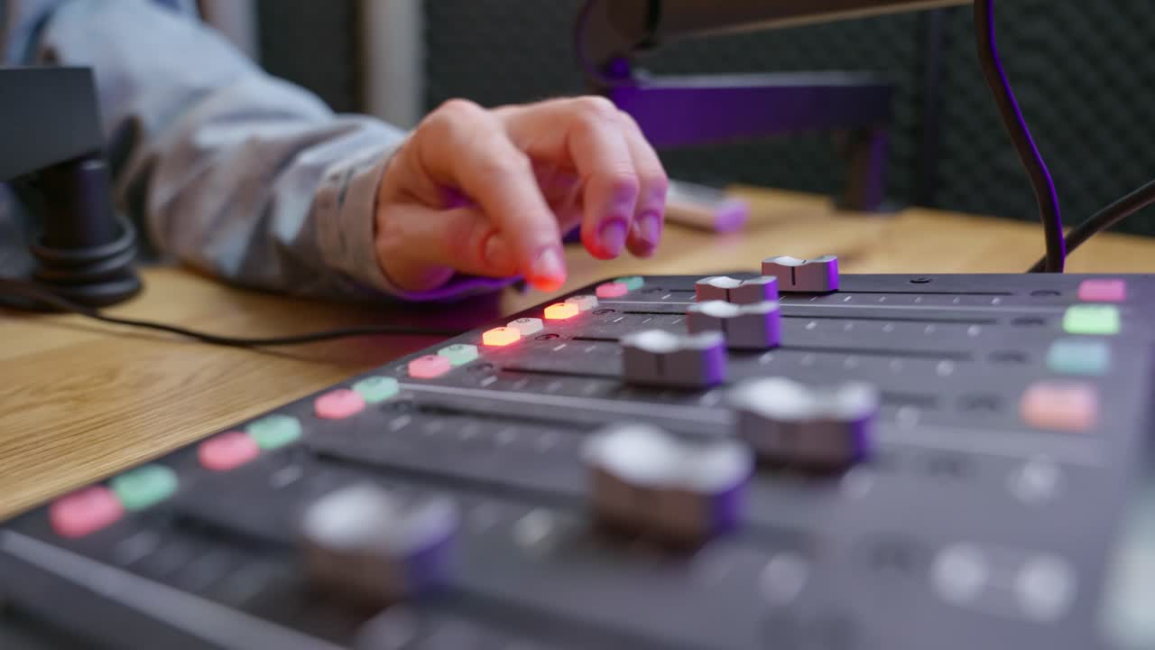 Close-up of hands adjusting knobs on a professional sound engineering console in a podcast or music studio. Audio production, mixing, fine-tuning sound quality. Music production, broadcasting, studio.