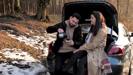 pareja caucásica tomando té caliente en un bosque nevado.