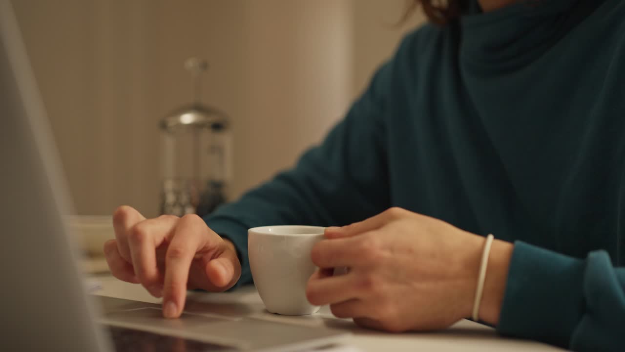 A person using a laptop while drinking coffee
